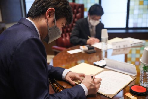 協定書に署名捺印をする様子