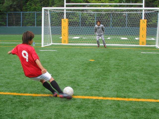 本学人工芝グラウンドで練習するサッカー部員